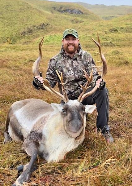 Hunter smiling with harvested Caribou bull