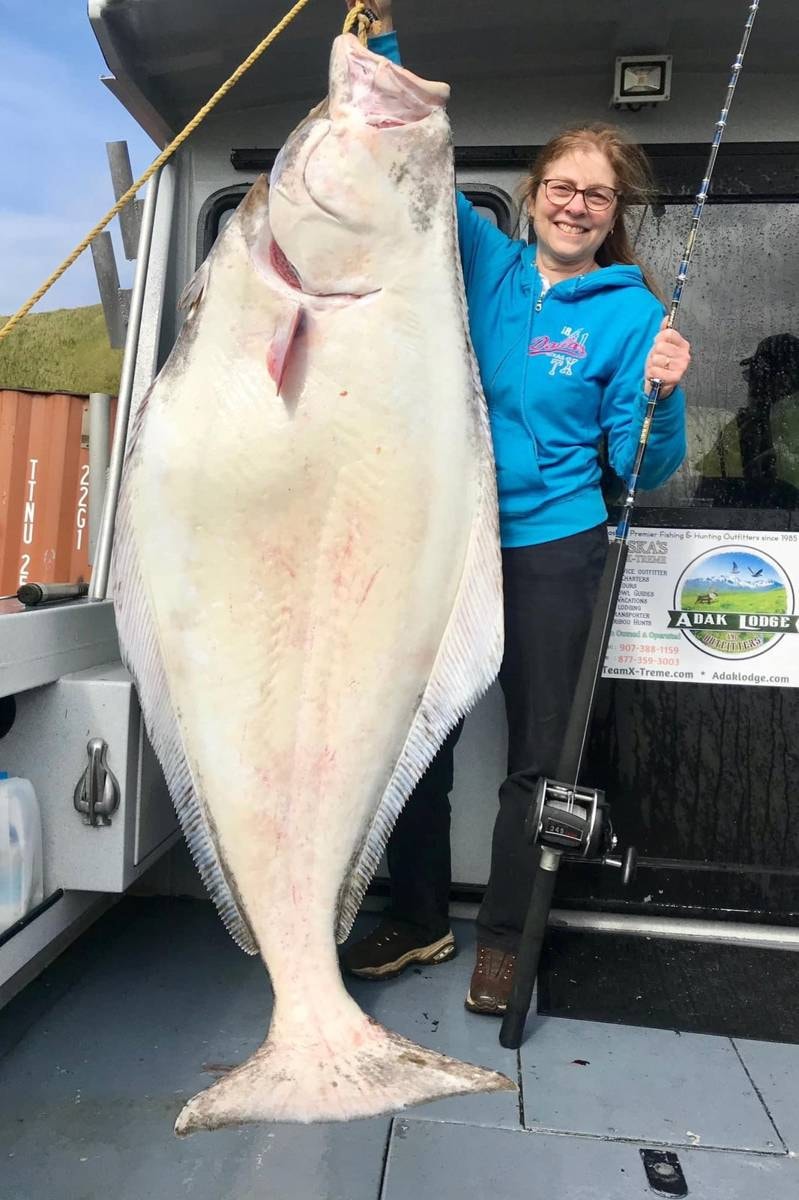 Woman posing with giant hanging halibut