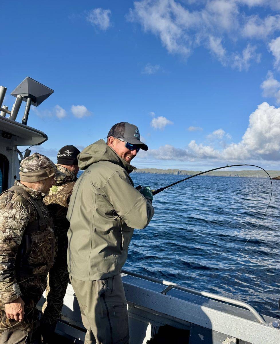 Three hunters fighting a fish off the boat rail