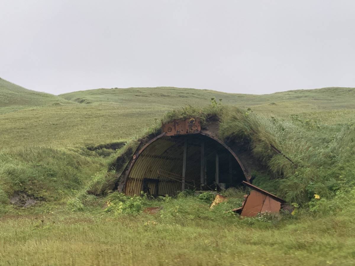 Rusted WWII Quonset hut half-buried in the Adak tundra