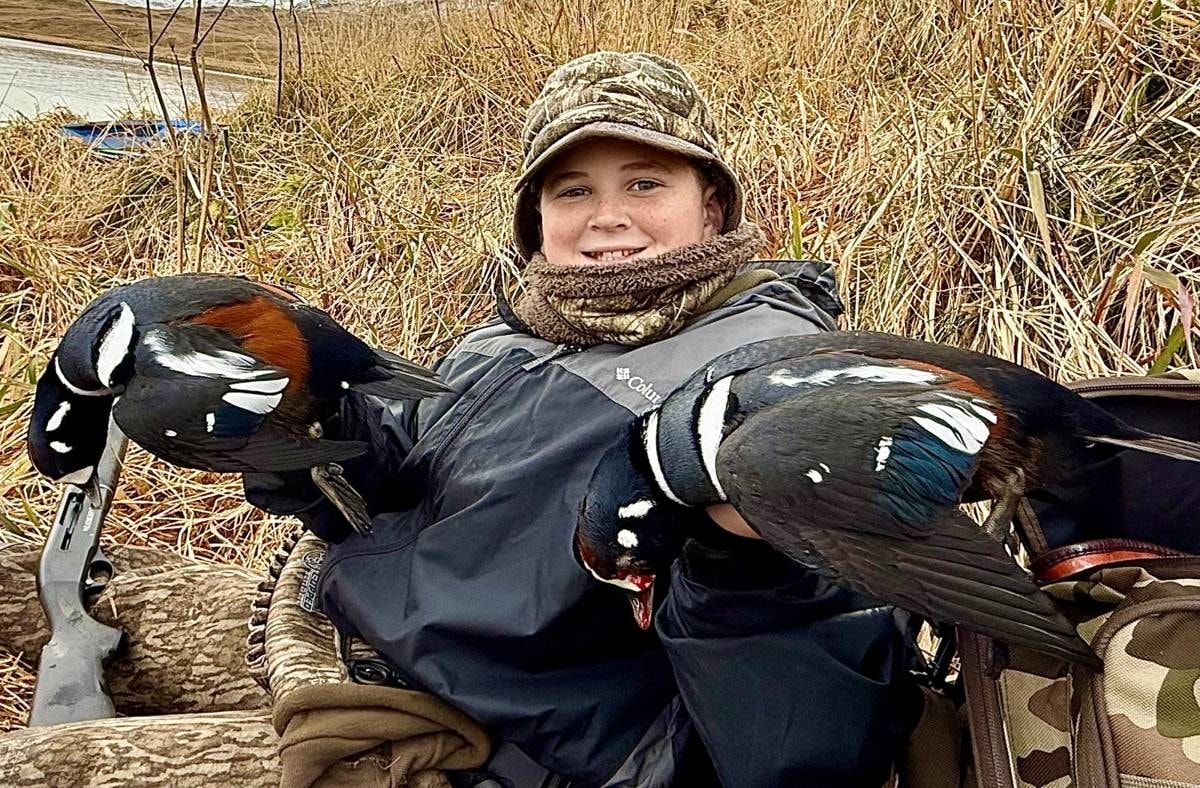 Kid hunter holding two Harlequin drakes on Adak