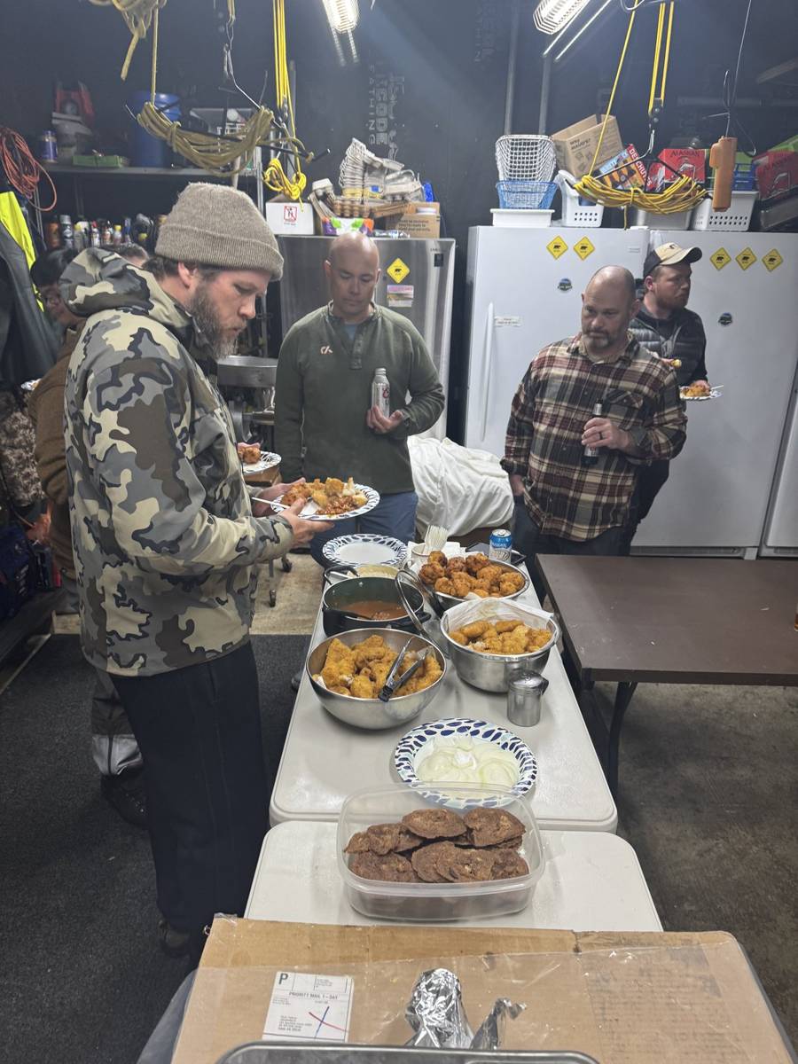 Hunters serving up a spread of fried fish, sides, and dessert